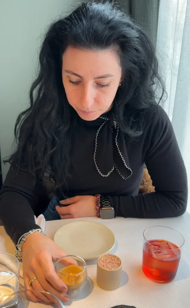 London food blogger enjoying a gourmet meal in a restaurant with a glass of espresso and a Negroni cocktail on the table. Sara Cellini, Exploring the Food Scene
