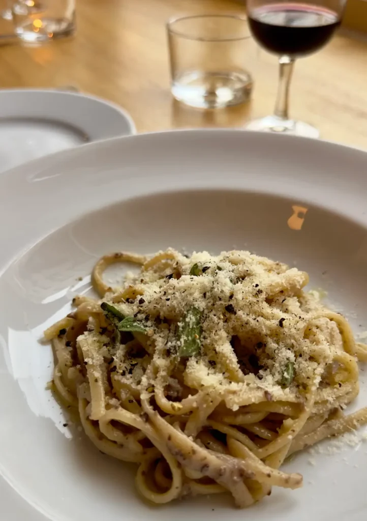 A plate of pasta topped with parmesan cheese and olives, featured in Darling's restaurant in London