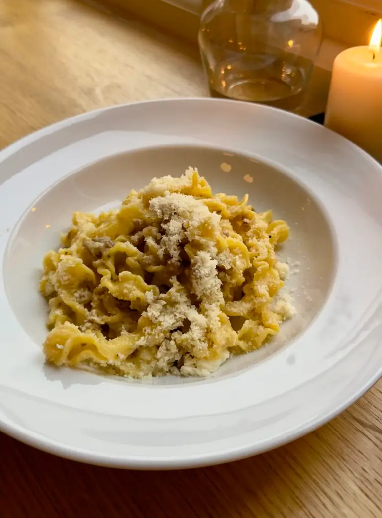 A candlelit table featuring a plate of Mafaldine pasta at Darling's Restaurant in London