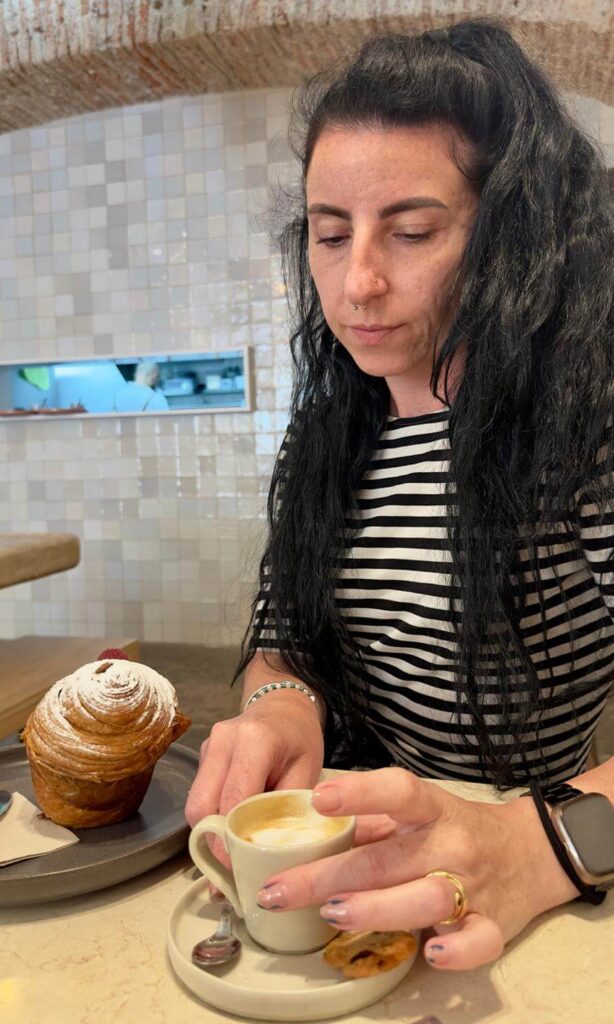 Myself while holding an espresso and a plate with a cruffin.