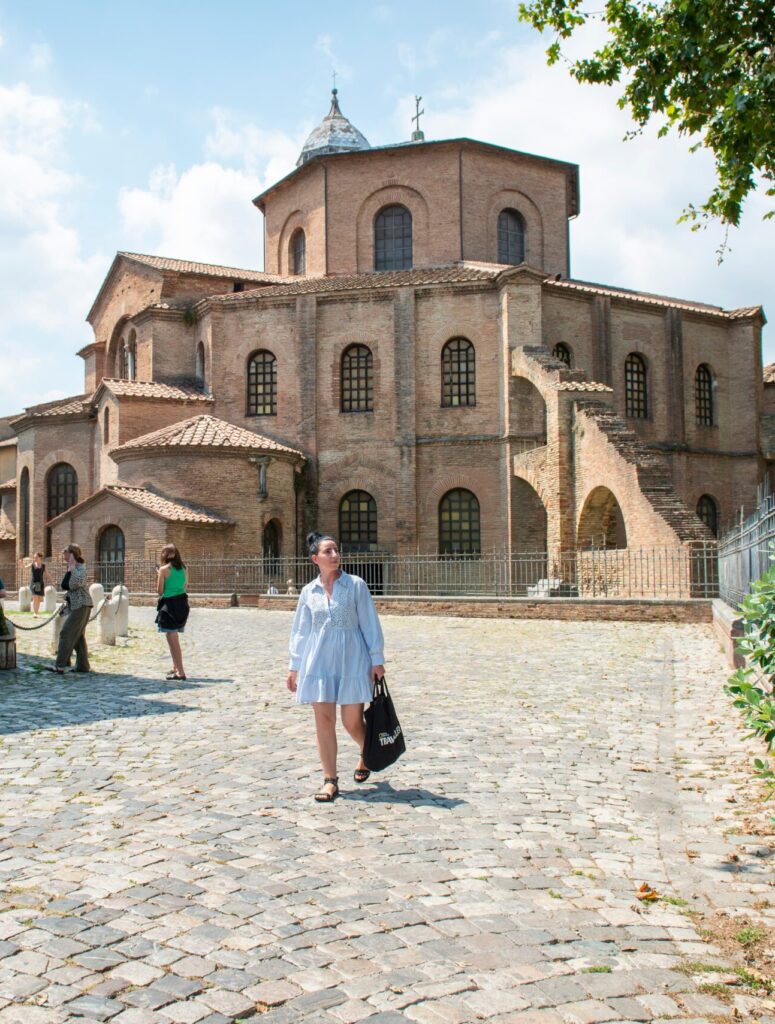 Myself walking in front of the Mausoleum of Gallia Placidia in Ravenna, while tourists admire the monuments.