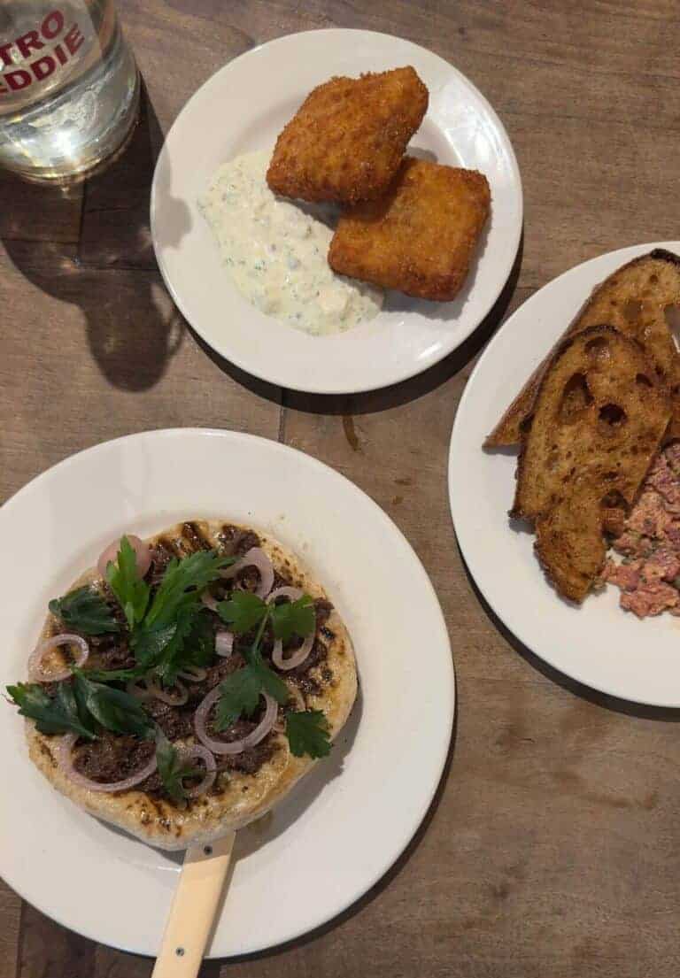 On the chef counter as starters at Bistro Freddie: a small flatbread served with beef cheek, onions and herbs. 2 slices of bread and steak tartare. Pigs head croquettes served with tartare sauce.