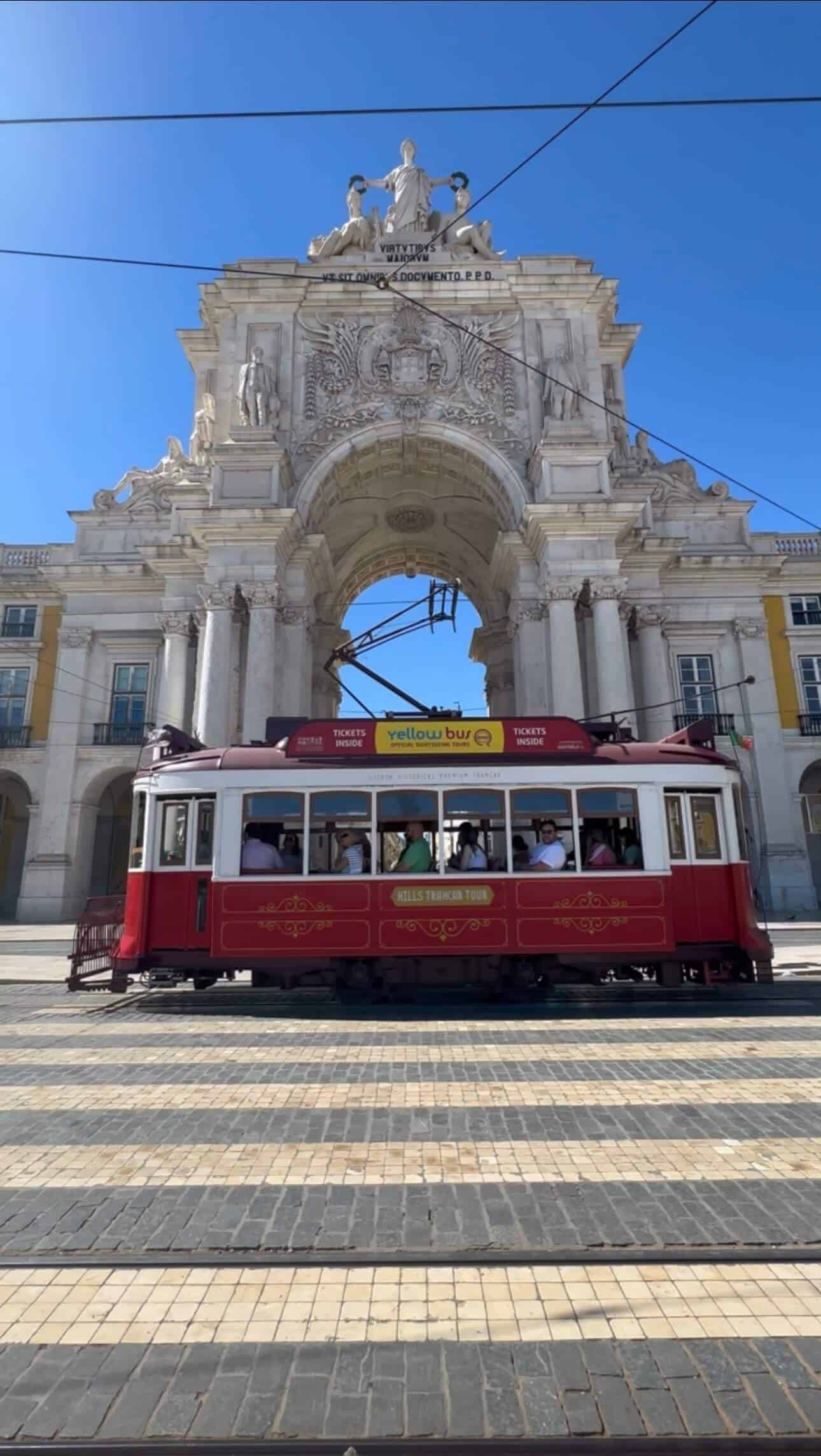 View of Arco da Rua Augusta while a traditional tram is passing in front