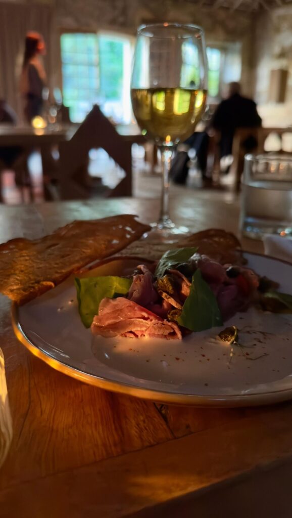 A plate of Vitello Tonnato served with flatbread and a glass of white wine at Palacio do Grilo, featured in a guide to the best restaurants in Lisbon