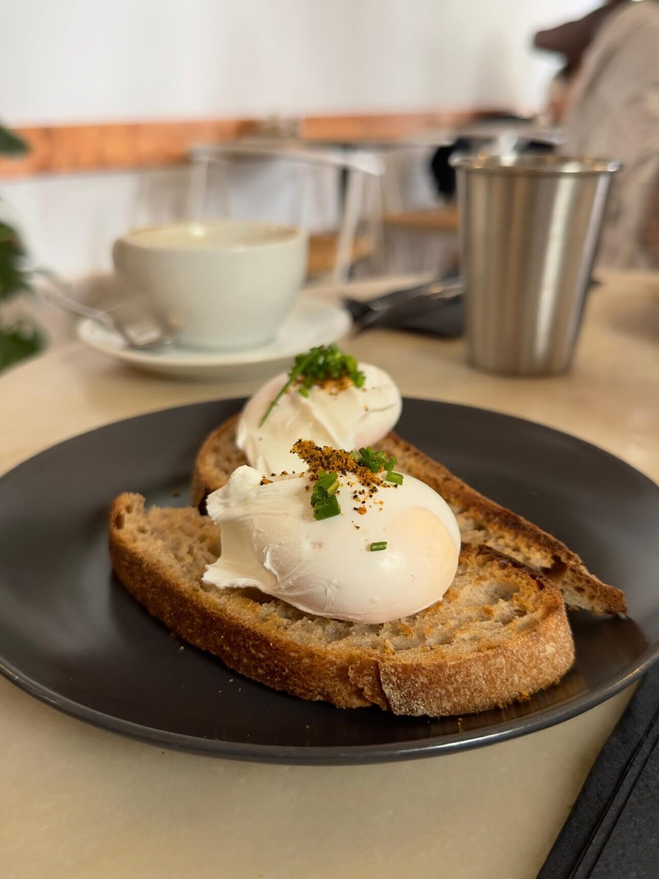 Two perfectly poached eggs topped with chives and spices on toasted sourdough bread at Dear Breakfast, a top spot for the best brunch in Alfama, Lisbon