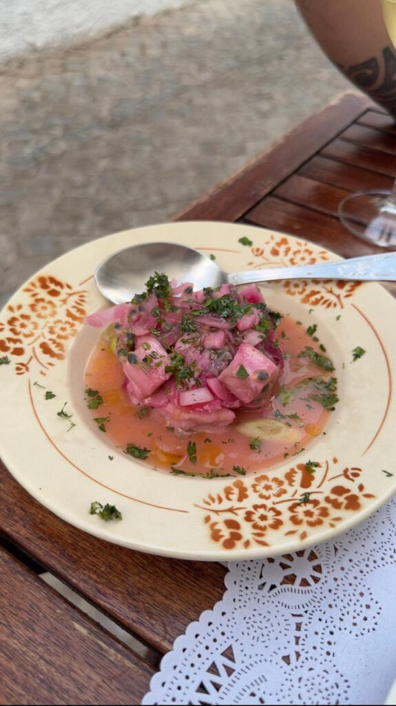 A refreshing Portuguese petisco plate at A Venda featuring diced pink fish ceviche with red onions, fresh herbs, and passion fruit seeds in a citrus broth.