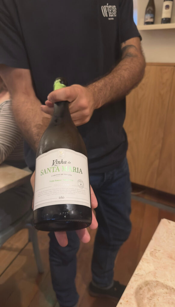 A waiter presenting a bottle of local Portuguese Vinha de Santa Maria white wine from the Dão region at Ofício Tasco Atípico, a trendy spot for where to eat in Lisbon
