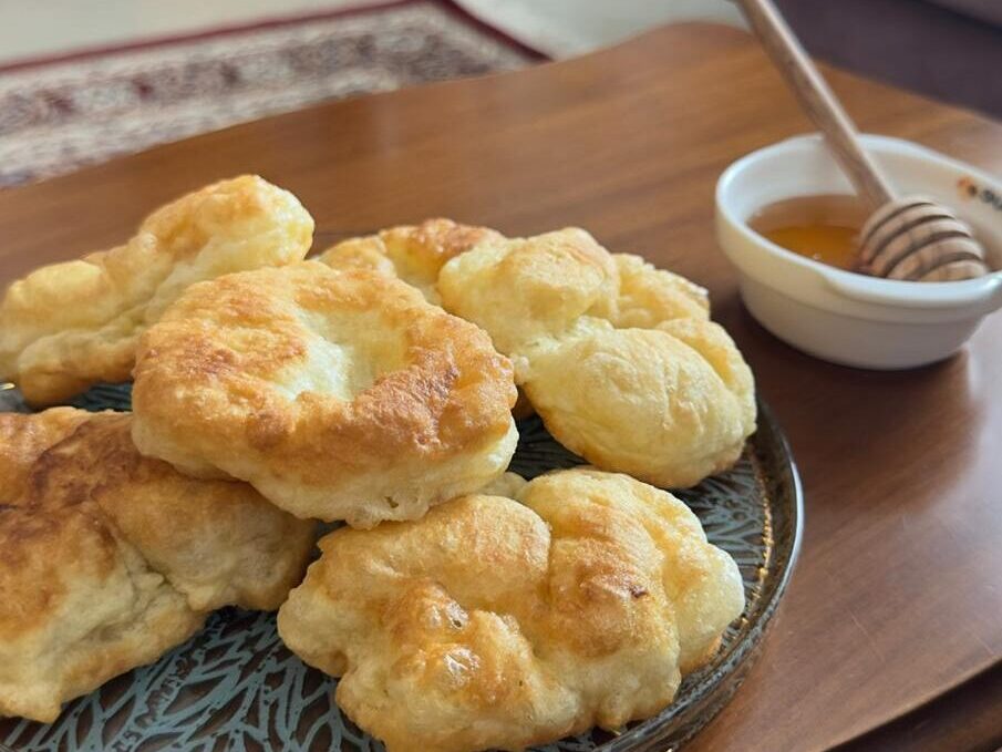 Plate of homemade Petulla served with honey in an Albanian home as a welcome gesture.